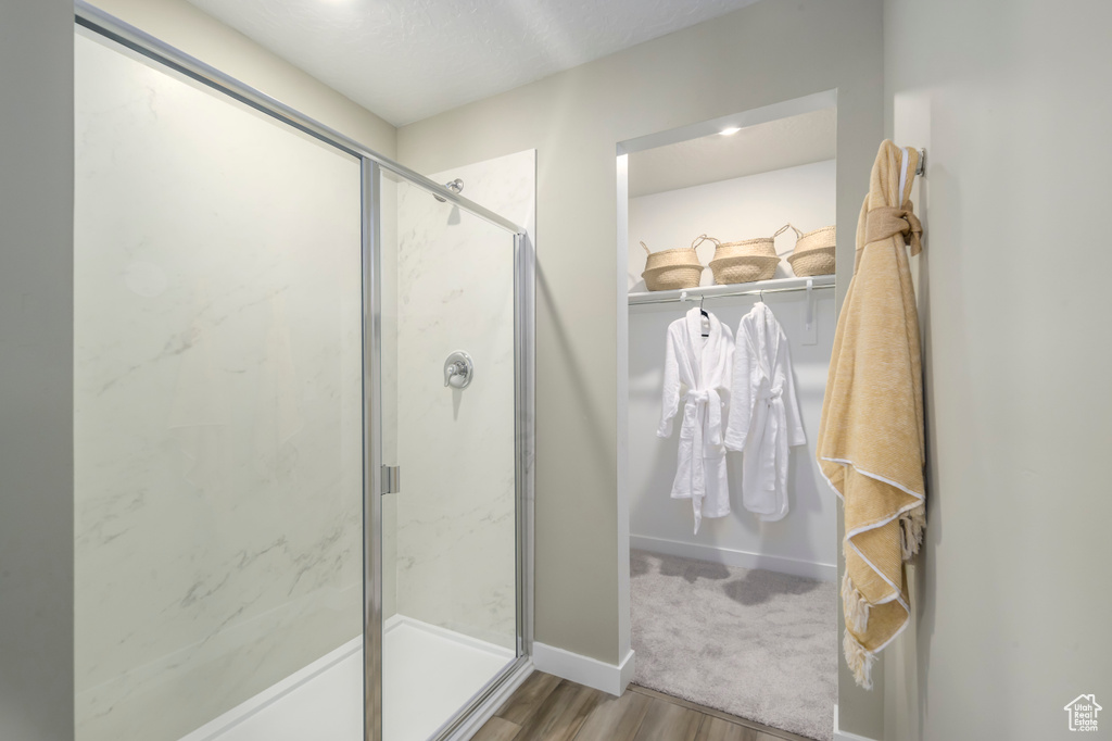 Bathroom with a marble finish shower, wood finished floors, and baseboards