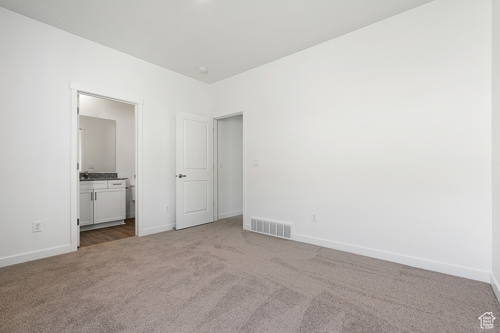 Unfurnished bedroom featuring carpet floors, baseboards, and ensuite bath