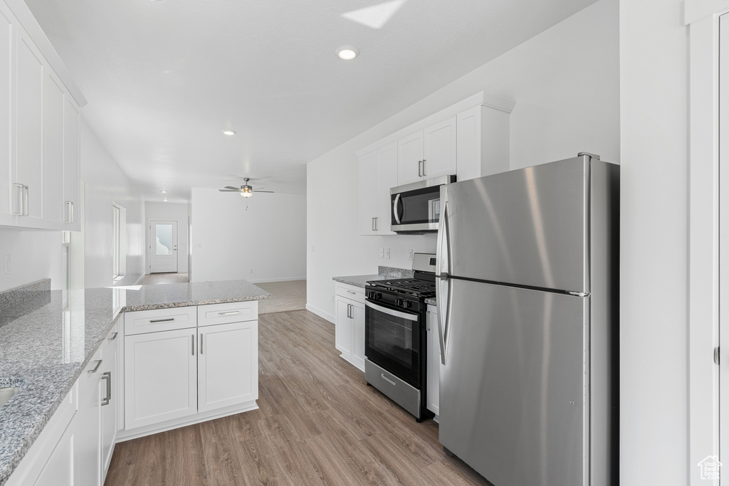 Kitchen featuring stainless steel appliances, white cabinetry, light wood finished floors, a peninsula, and recessed lighting