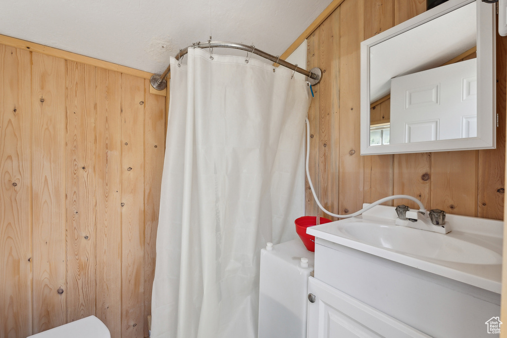 Bathroom with vanity, curtained shower, wooden walls, and toilet