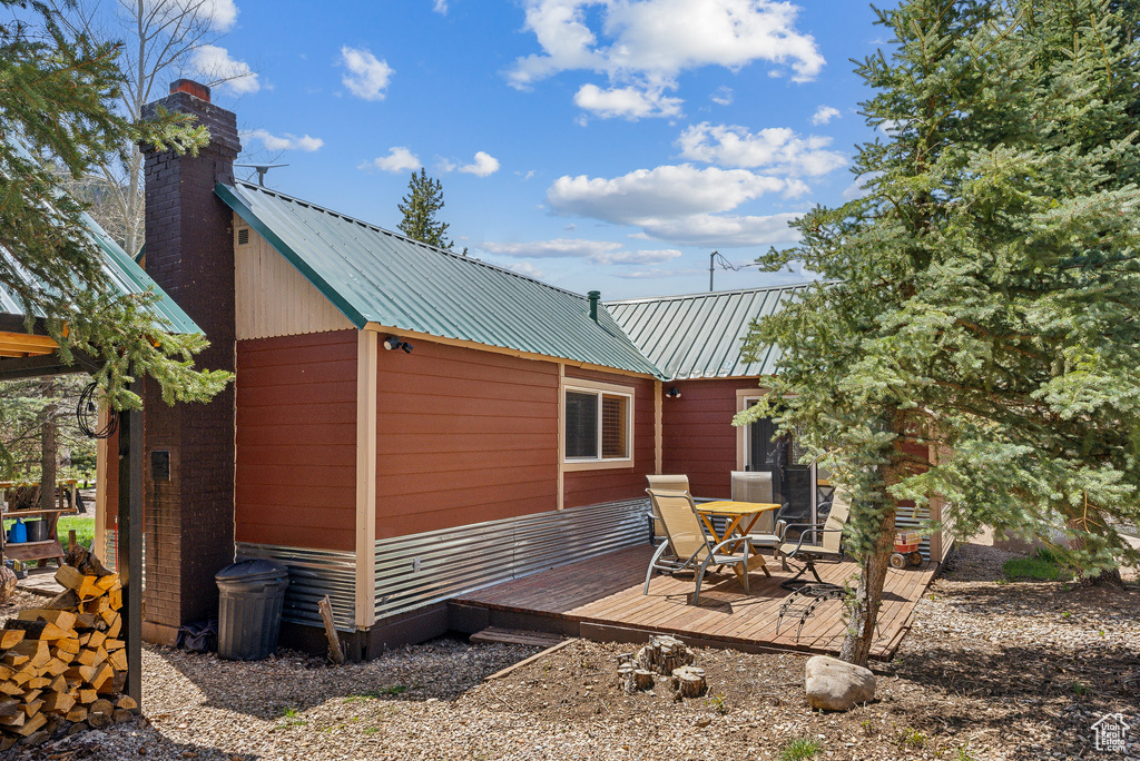 View of home's exterior featuring a wooden deck, a chimney, and metal roof