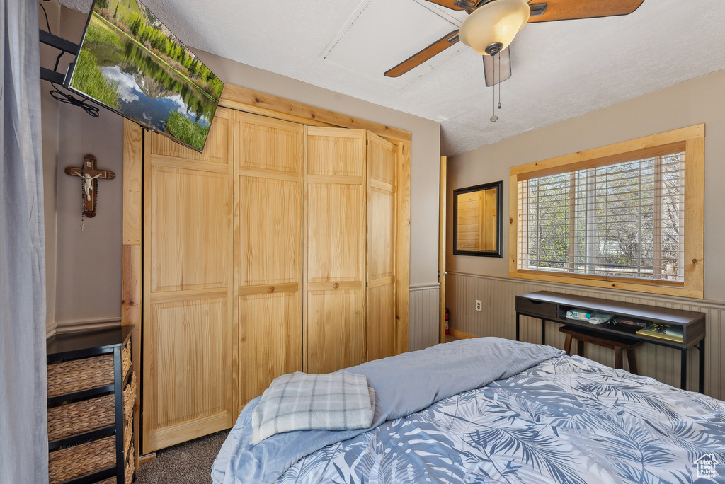 Carpeted bedroom with wainscoting and ceiling fan