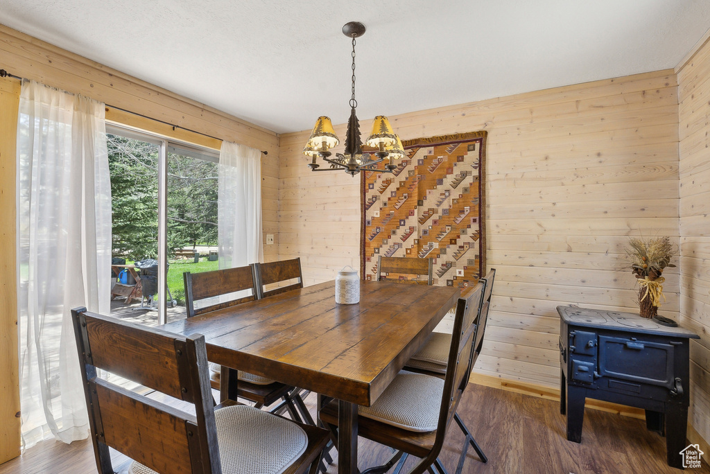 Dining area with a chandelier, wood walls, and wood finished floors