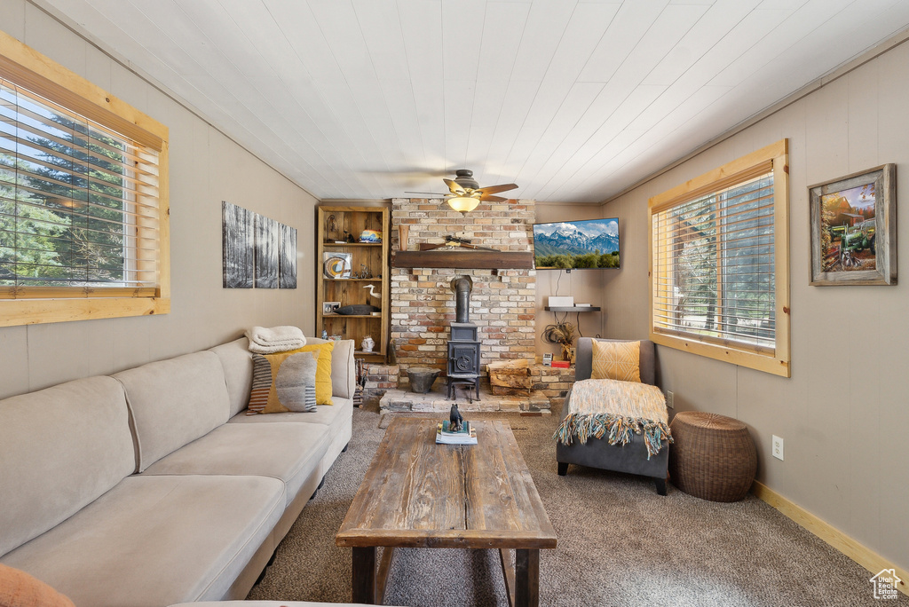 Carpeted living room featuring a wood stove, a ceiling fan, and built in shelves