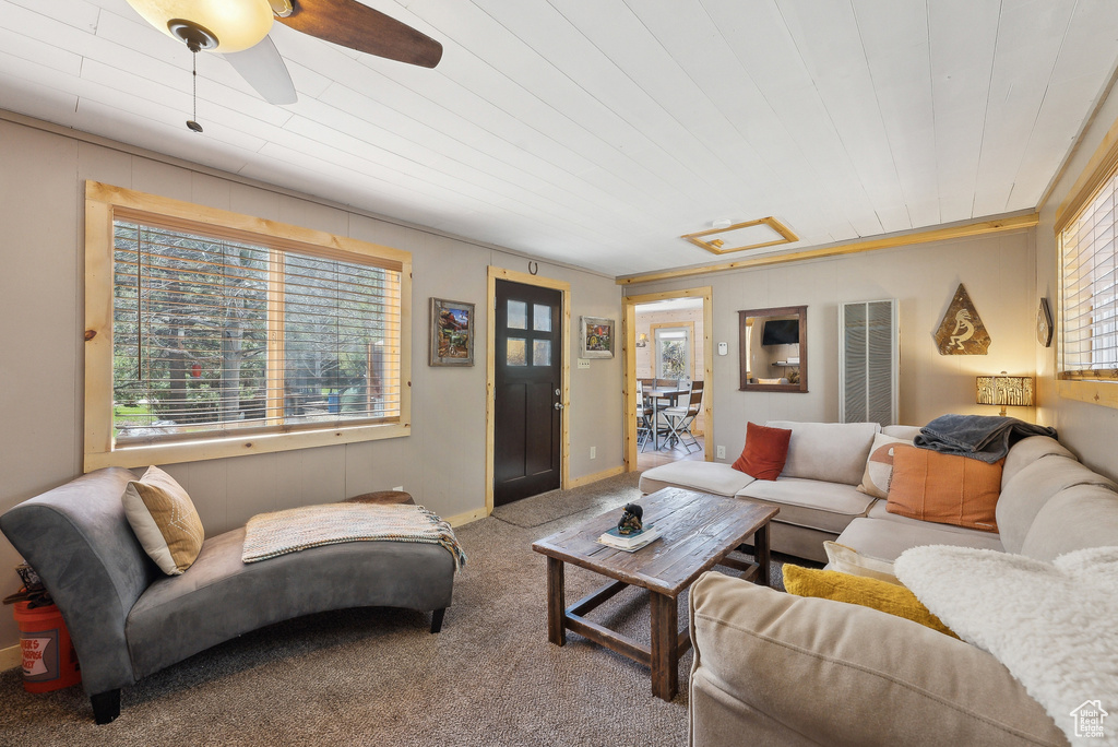 Living area featuring carpet flooring, ceiling fan, and wooden ceiling