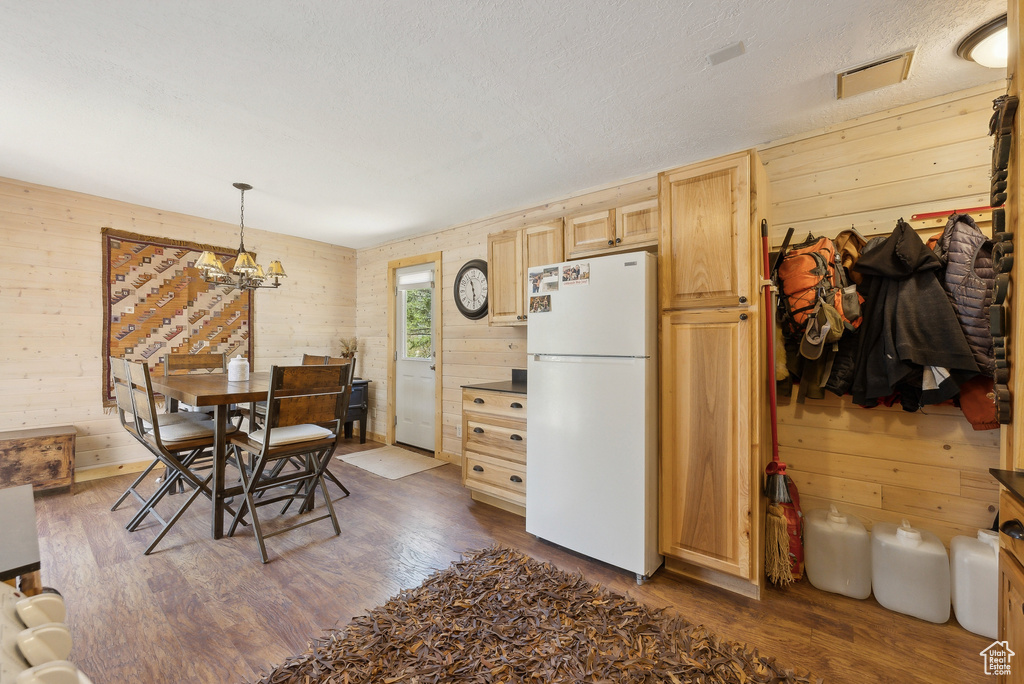 Dining room featuring dark wood finished floors, wood walls, and a chandelier