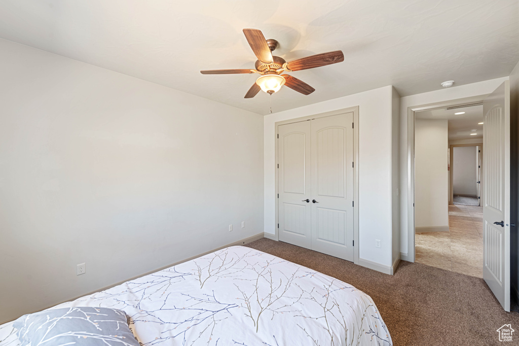Carpeted bedroom featuring baseboards, a closet, and ceiling fan