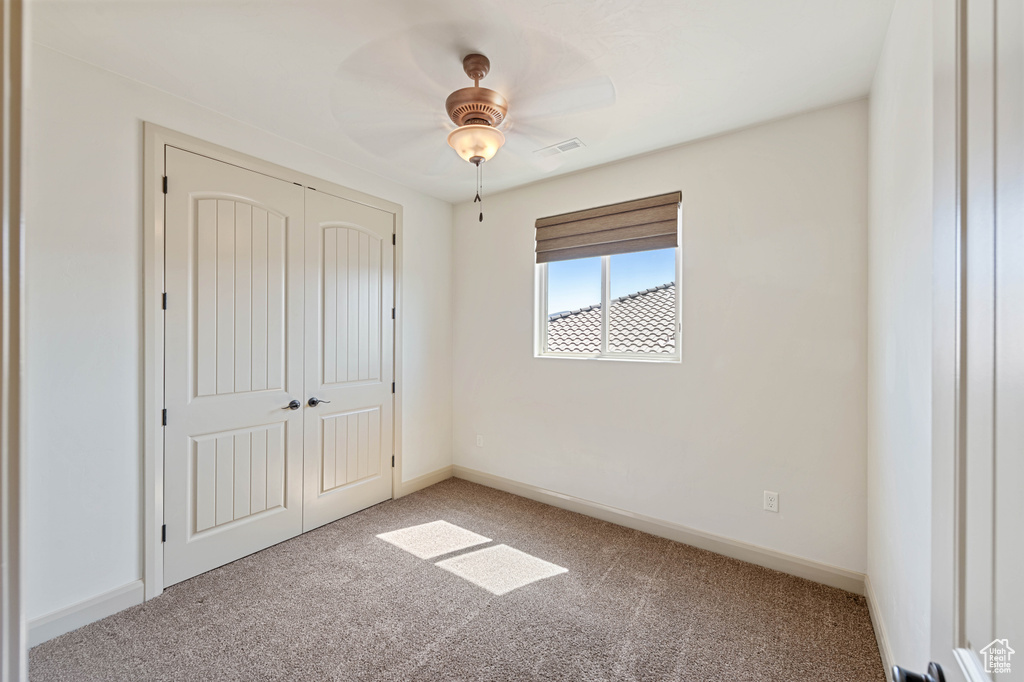 Unfurnished bedroom featuring light carpet, a closet, baseboards, and ceiling fan