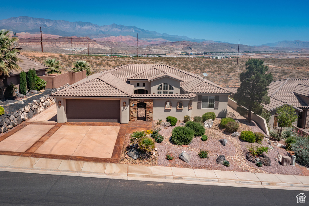 Mediterranean / spanish-style house with a mountain view, a garage, stucco siding, and a tile roof