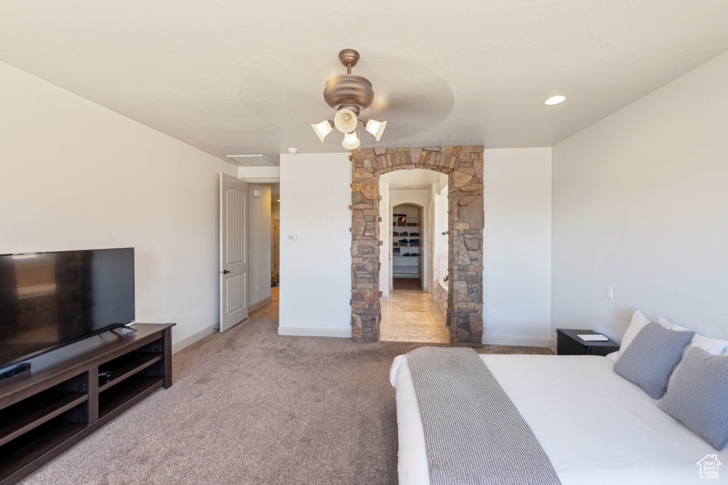 Carpeted bedroom featuring arched walkways, baseboards, and ceiling fan