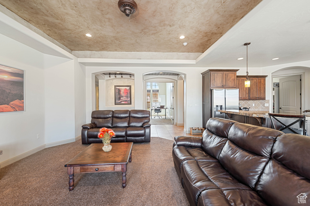 Living room featuring arched walkways, baseboards, recessed lighting, and a tray ceiling