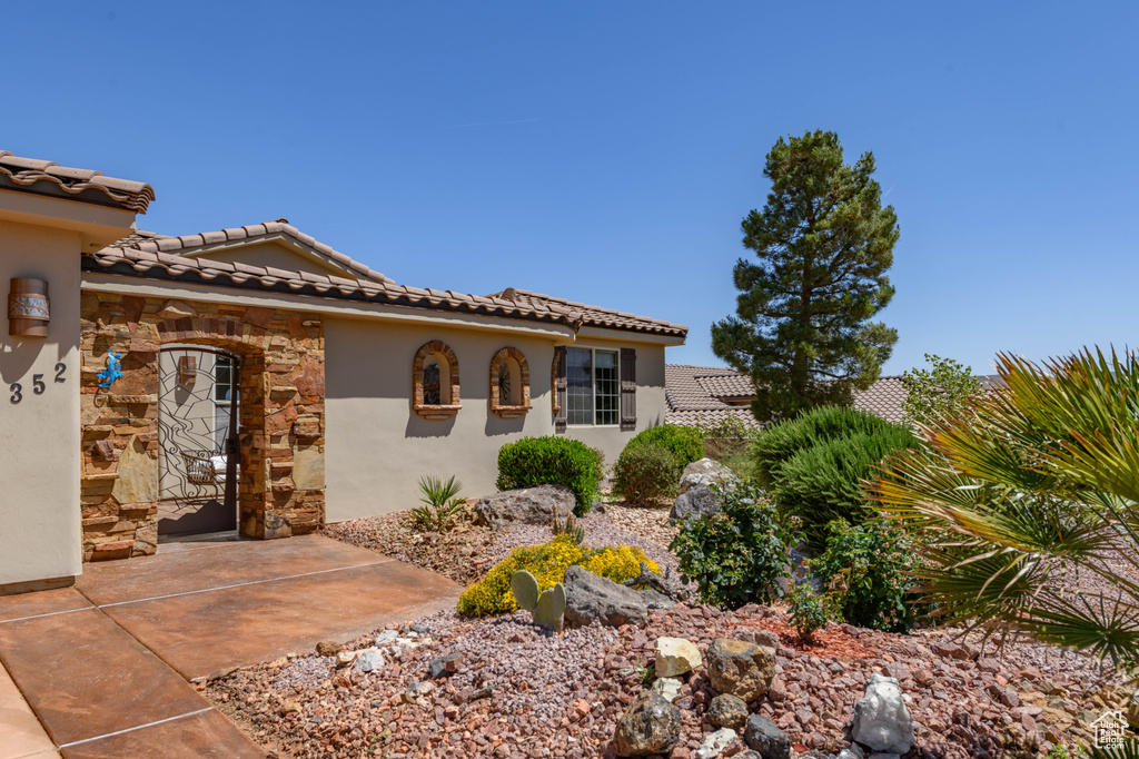 View of front of property featuring stone siding, a tiled roof, and stucco siding