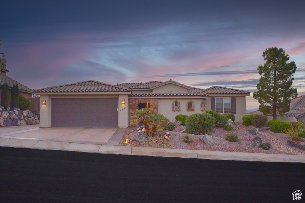 Mediterranean / spanish-style house featuring stucco siding, a garage, a tiled roof, and driveway