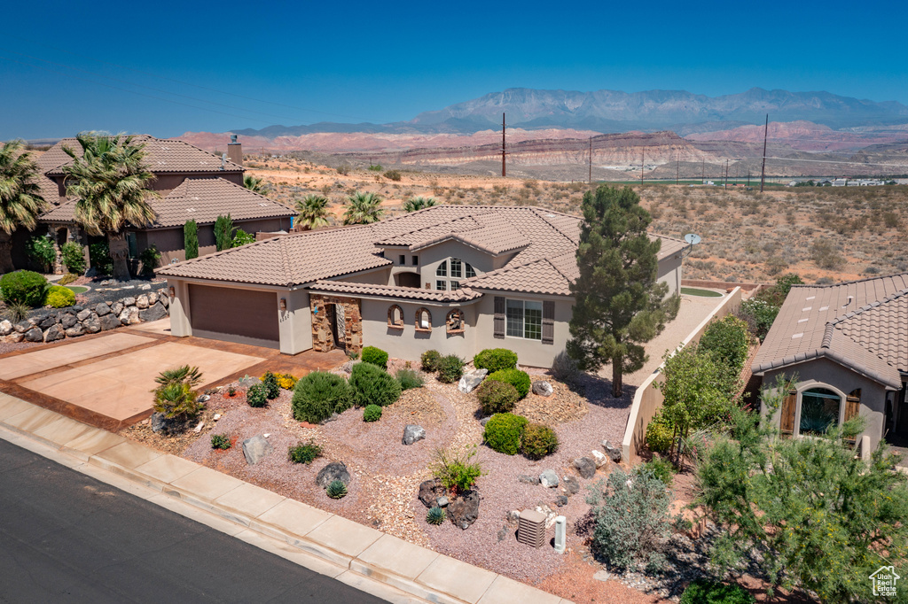 View of front of property with a mountain view, a tiled roof, a garage, and stucco siding