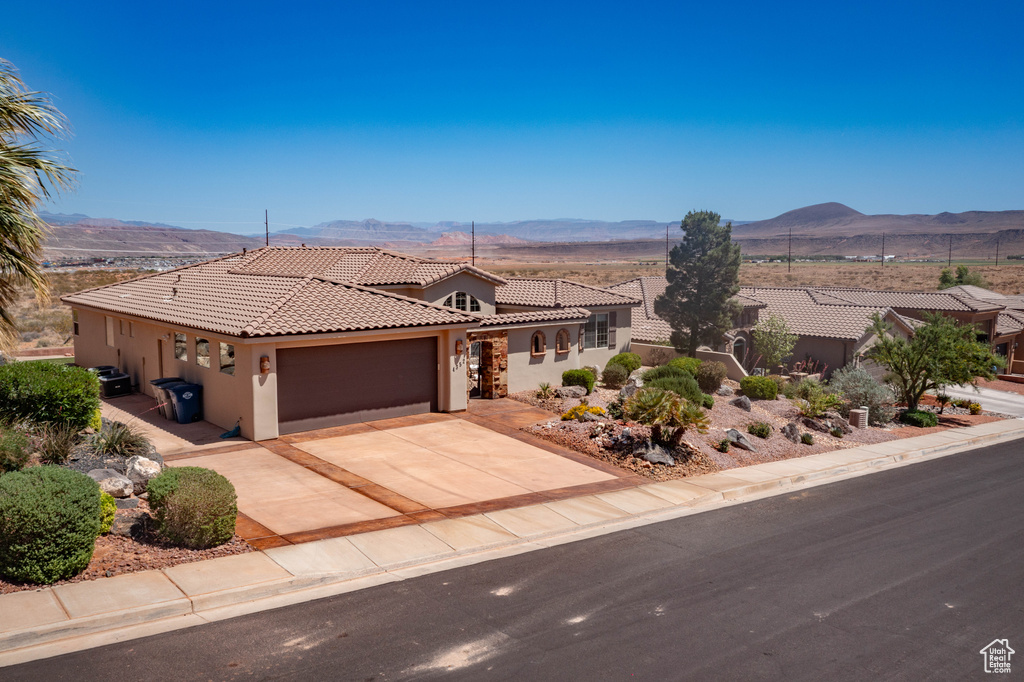Mediterranean / spanish-style house featuring a tiled roof, stucco siding, a mountain view, an attached garage, and concrete driveway
