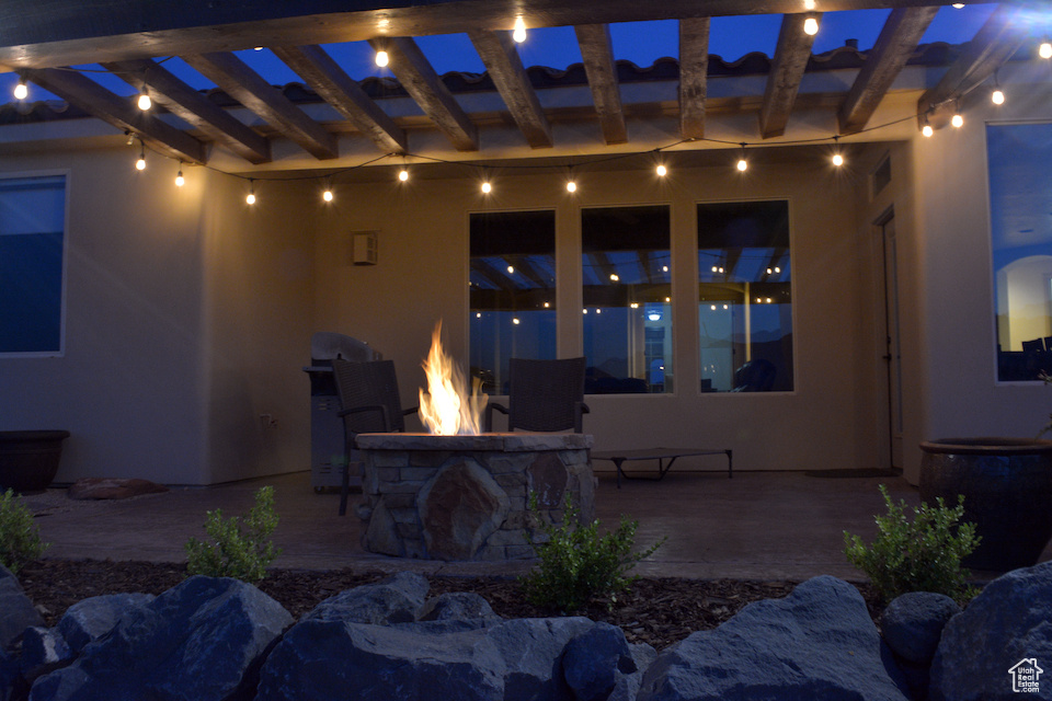 Patio at night featuring an outdoor fire pit and a patio area