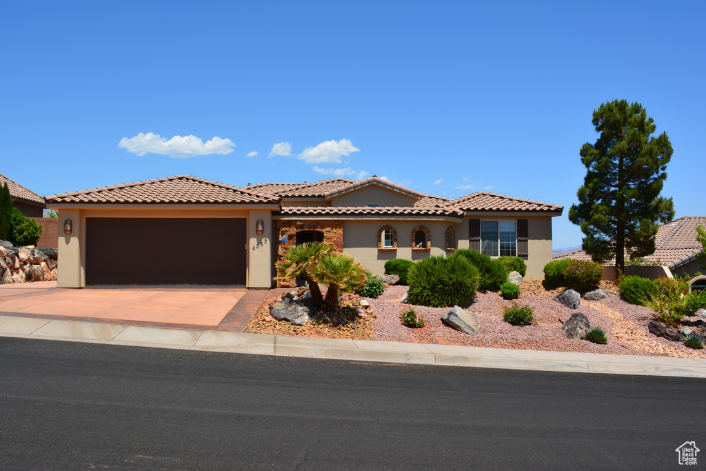 Mediterranean / spanish house featuring stucco siding, an attached garage, concrete driveway, and a tile roof