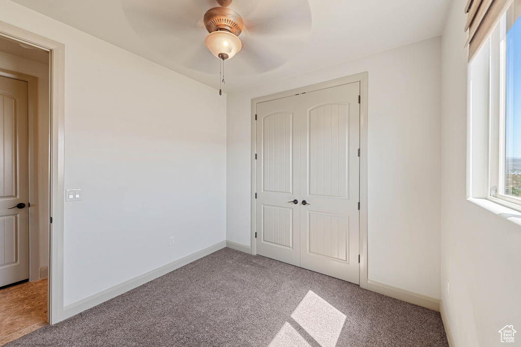 Unfurnished bedroom with carpet flooring, a closet, a ceiling fan, and baseboards