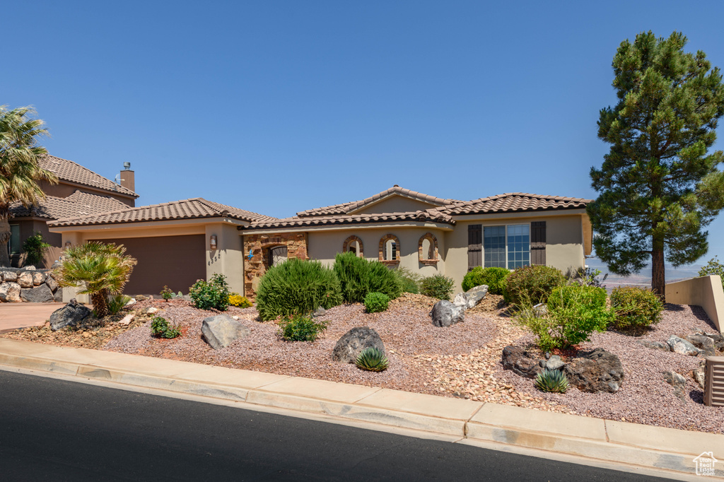 Mediterranean / spanish home with stucco siding, an attached garage, and a tiled roof