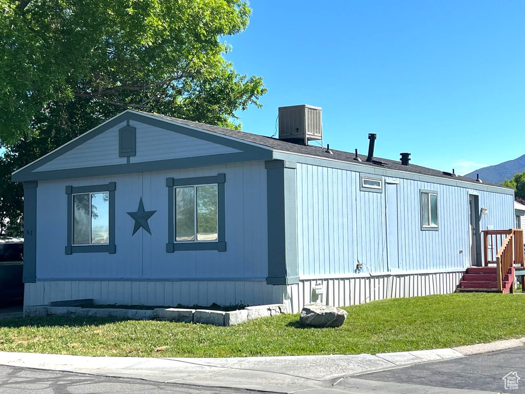 View of side of property featuring a yard and central AC