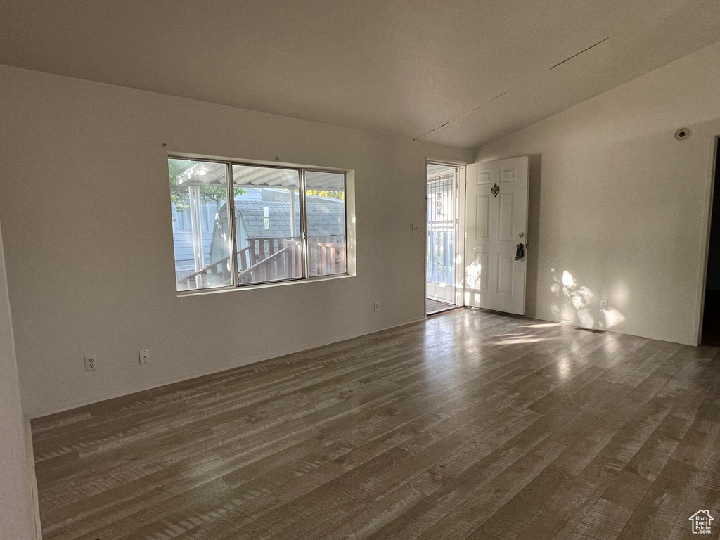 Empty room with vaulted ceiling and wood finished floors
