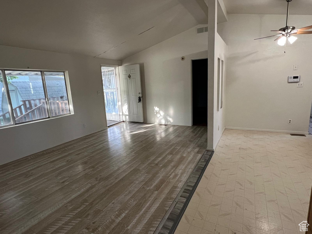 Unfurnished living room featuring lofted ceiling, healthy amount of natural light, ceiling fan, and wood finished floors