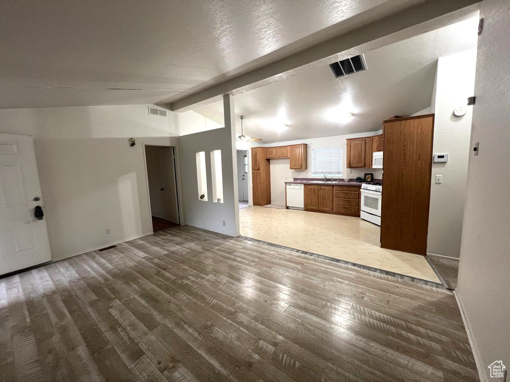 Unfurnished living room featuring wood finished floors, a sink, baseboards, and a ceiling fan