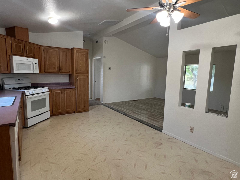 Kitchen with white appliances, a ceiling fan, baseboards, open floor plan, and light flooring