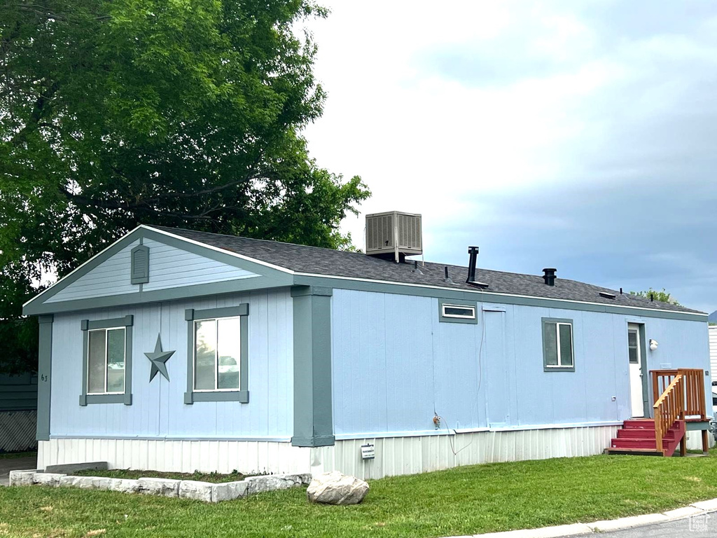 View of side of property with cooling unit and a yard