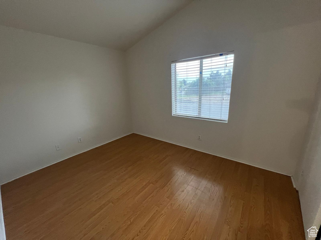 Empty room featuring wood finished floors and lofted ceiling