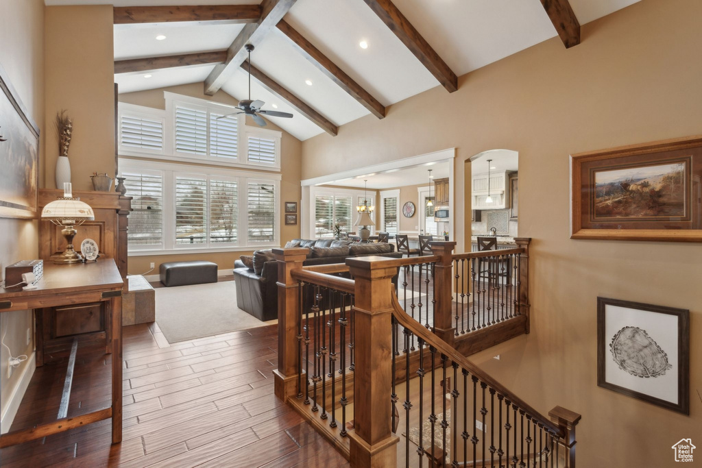 Living area featuring ceiling fan, beam ceiling, wood finished floors, arched walkways, and high vaulted ceiling