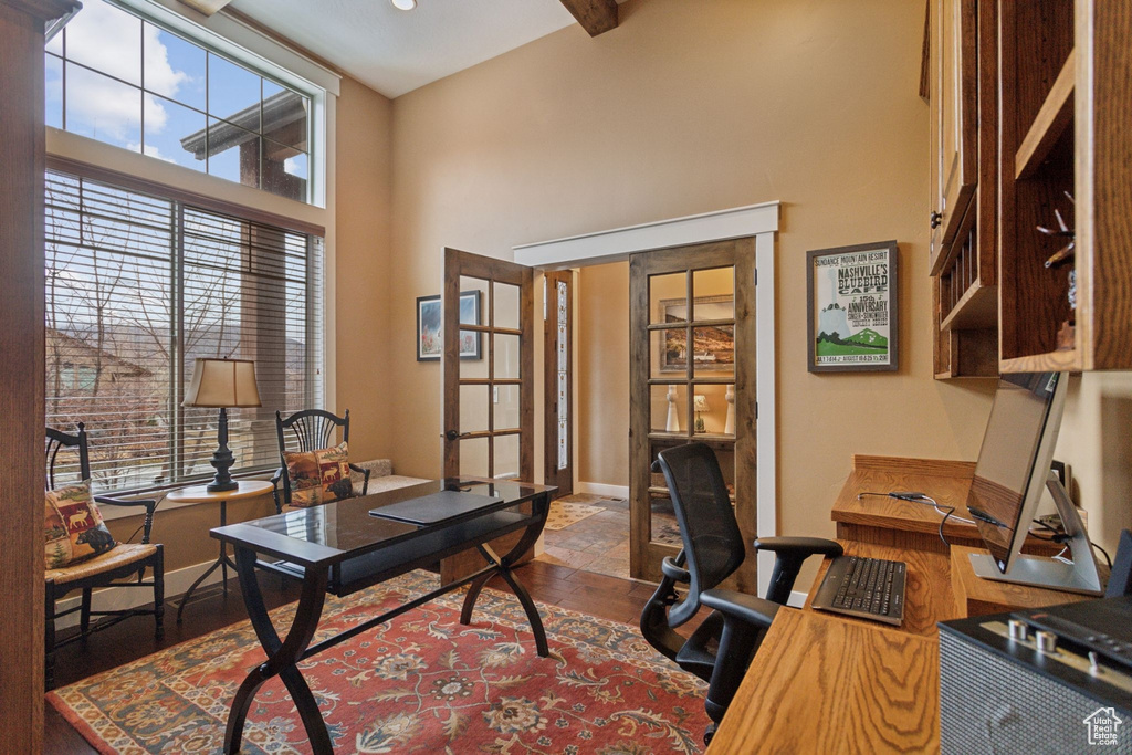 Home office featuring a high ceiling, french doors, and baseboards