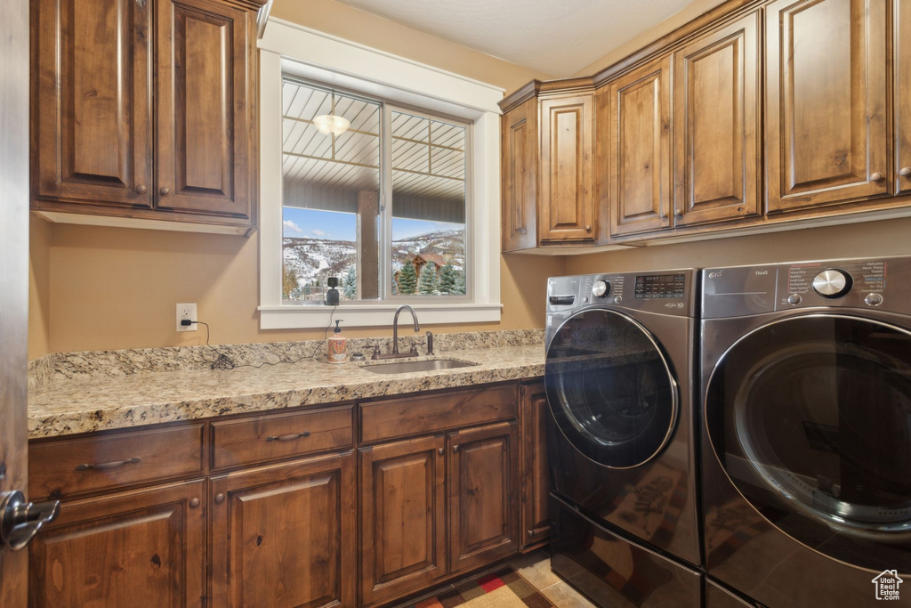 Clothes washing area featuring cabinet space and washer and dryer