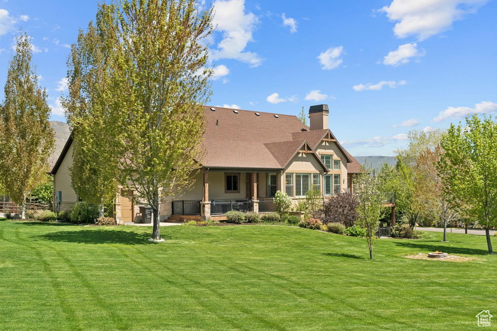 Back of property featuring a yard, a chimney, an outdoor fire pit, and stucco siding