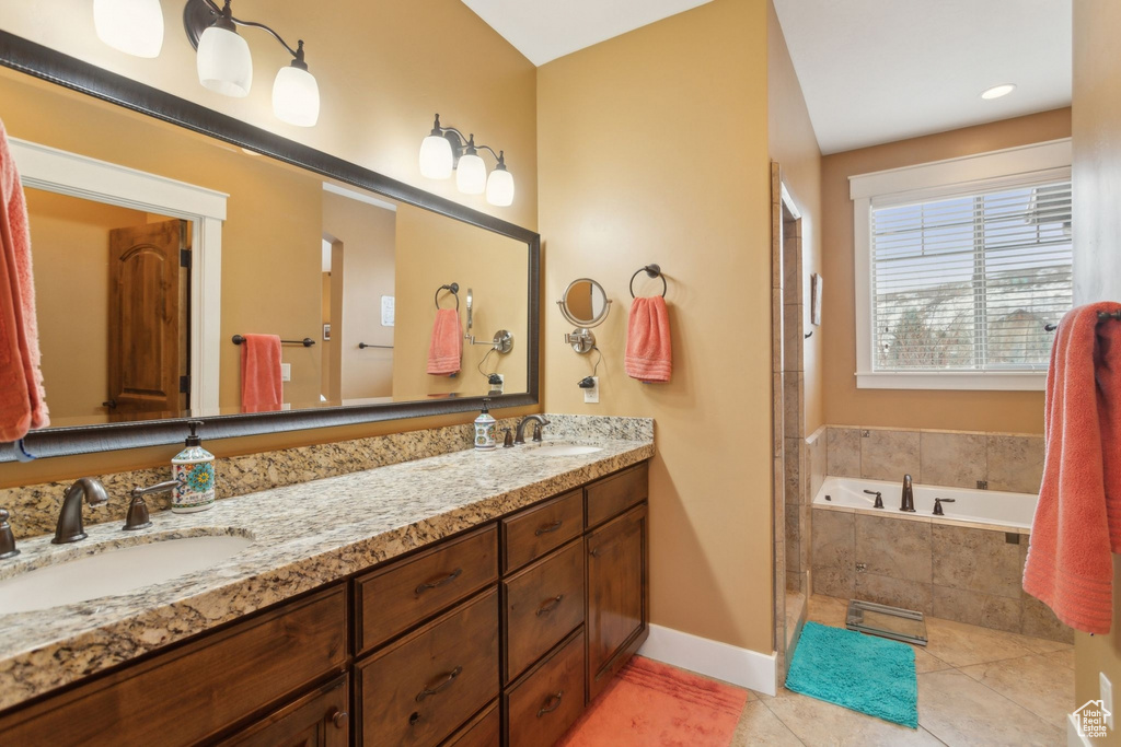 Bathroom featuring baseboards, tile patterned flooring, a bath, and double vanity