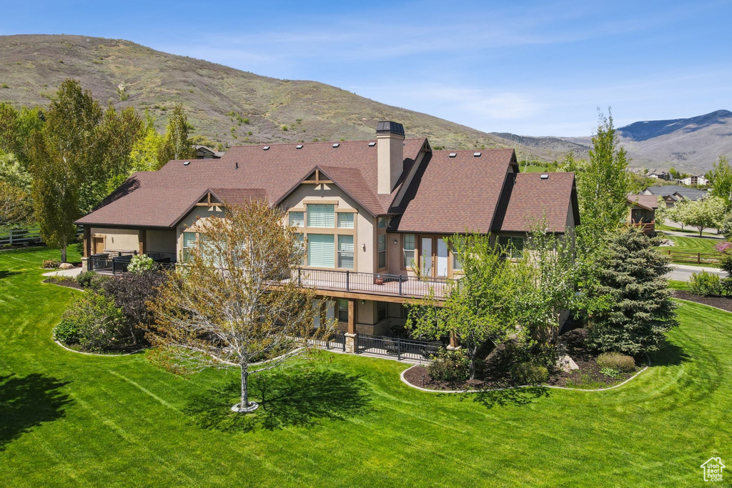 Back of house featuring a chimney, a lawn, a mountain view, and a patio