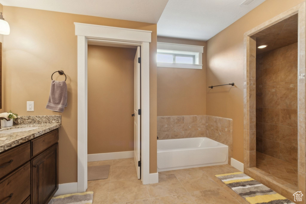 Bathroom featuring a bath, vanity, a tile shower, tile patterned flooring, and baseboards