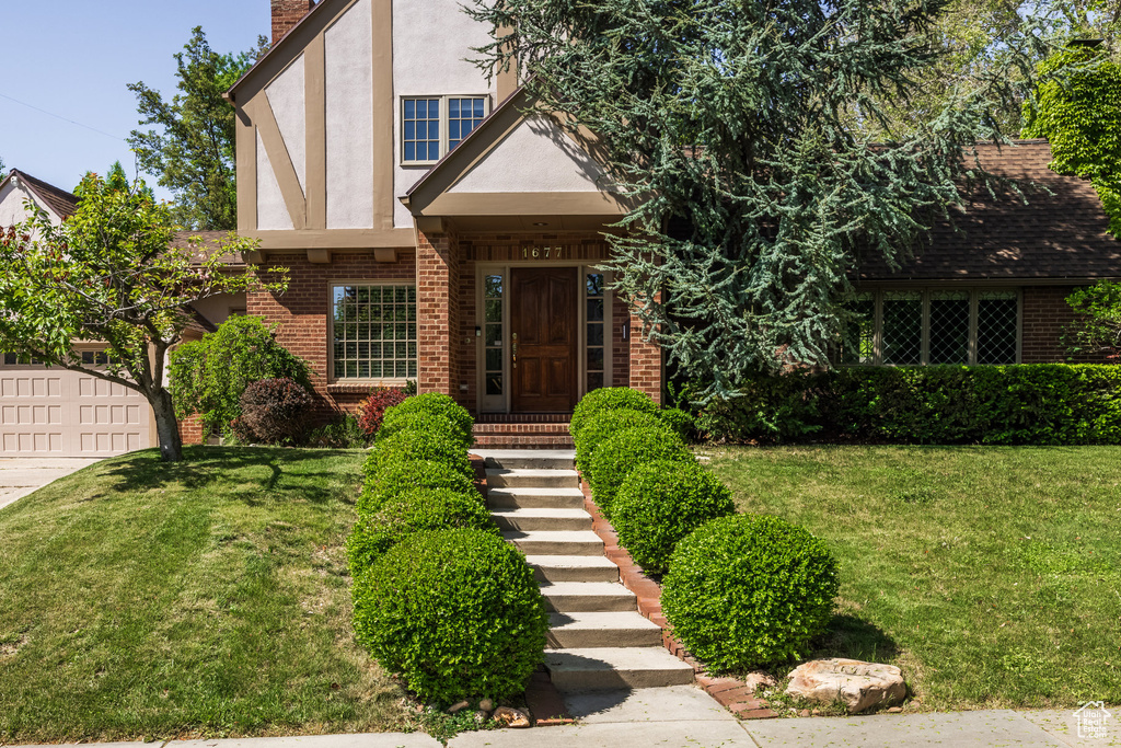 Tudor home featuring brick siding, stucco siding, and a front yard