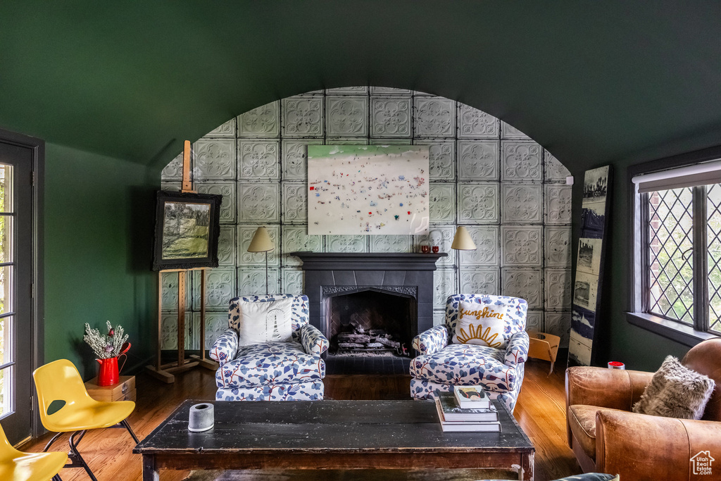 Living area with wood finished floors, lofted ceiling, and a tile fireplace