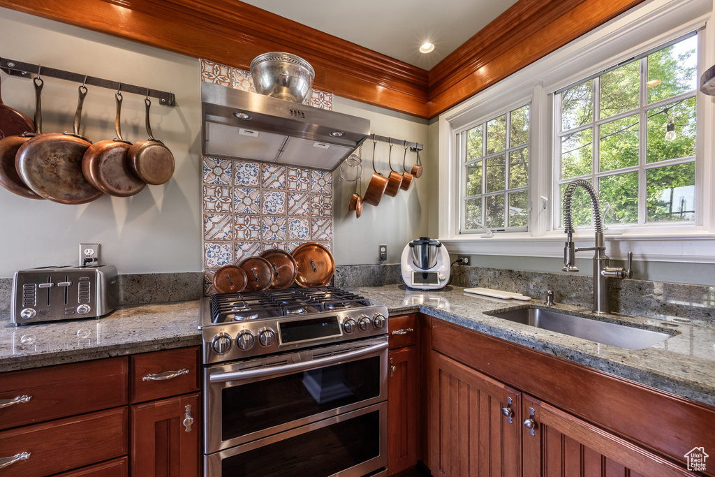 Kitchen with double oven range, a sink, exhaust hood, and stone countertops