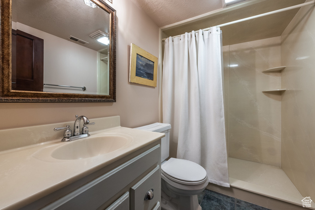 Bathroom featuring toilet, curtained shower, vanity, and a textured ceiling
