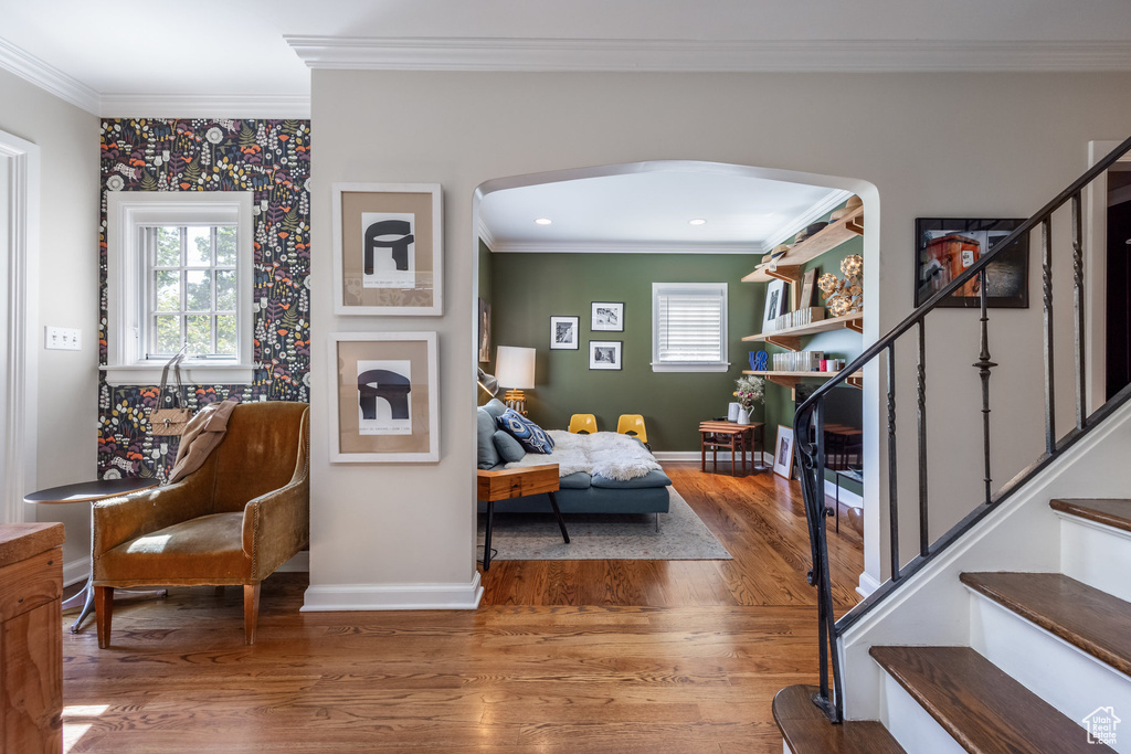 Living area featuring ornamental molding, plenty of natural light, stairway, arched walkways, and wood finished floors