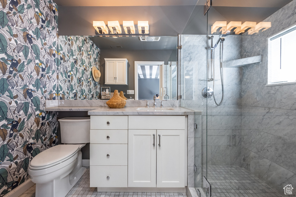 Bathroom featuring a stall shower, toilet, vanity, and wallpapered walls