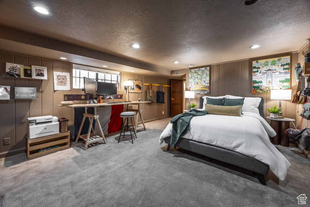 Carpeted bedroom with a textured ceiling, recessed lighting, and a decorative wall