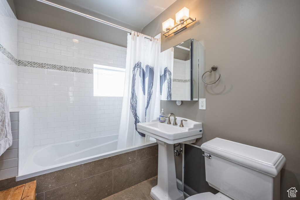 Bathroom with toilet, tiled shower / bath combo, and tile patterned floors