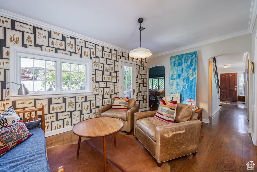 Living area featuring arched walkways, wood finished floors, ornamental molding, baseboards, and stairs