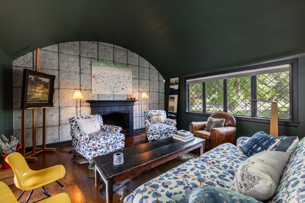 Living room featuring wood finished floors, a fireplace, and lofted ceiling