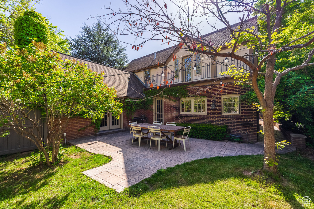 Back of house featuring french doors, a balcony, a patio, and brick siding