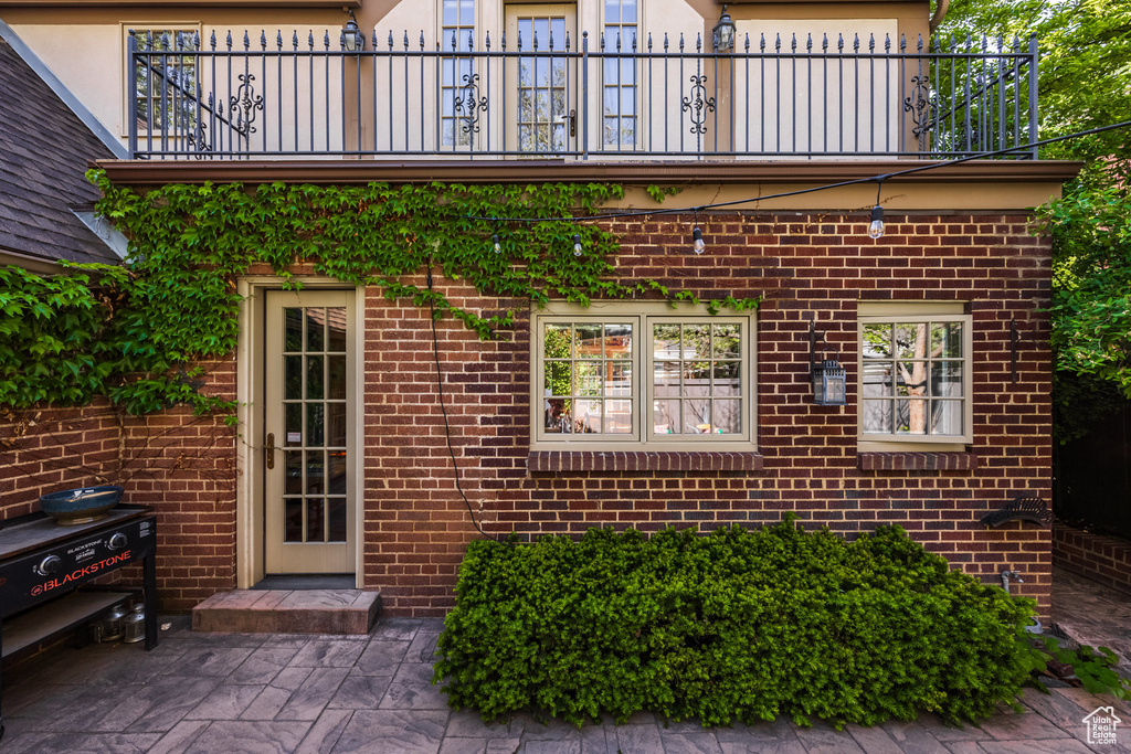 View of exterior entry featuring a balcony and brick siding