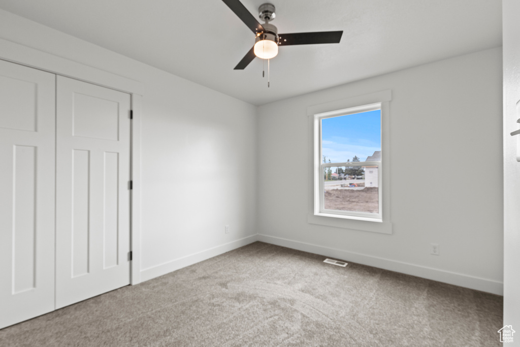 Unfurnished bedroom featuring baseboards, carpet flooring, a ceiling fan, and a closet